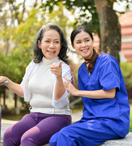 caregiver and elderly woman sitting on the bench outside